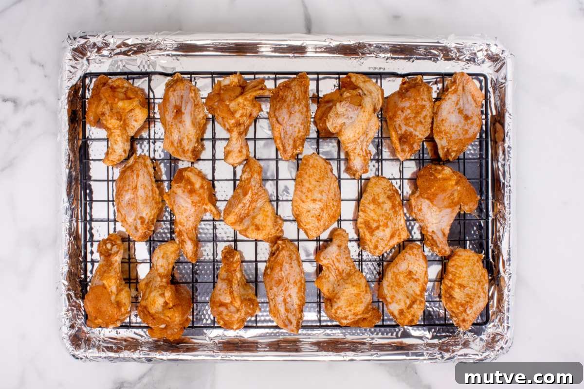 Extra Crispy Oven-Baked Chicken Wings Recipe 6 chicken wings on rack on top of foil lined baking sheet before baking.