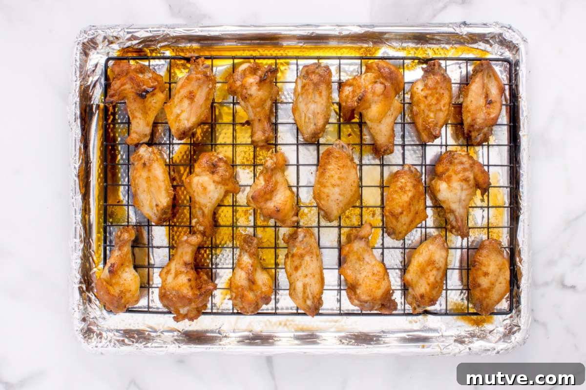 Extra Crispy Oven-Baked Chicken Wings Recipe 7 baked chicken wings on wire rack on top of baking sheet.
