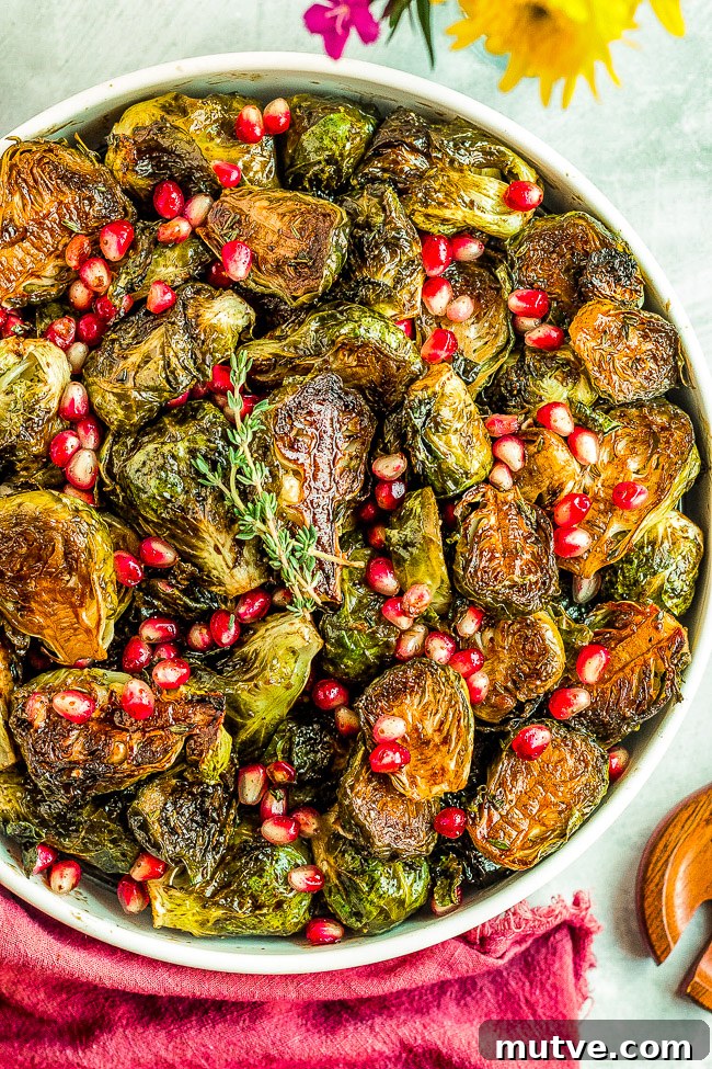 Balsamic Glazed Brussels Sprouts with Pomegranate Seeds 5 Roasted brussels sprouts garnished with pomegranate seeds and fresh herbs in a serving bowl.
