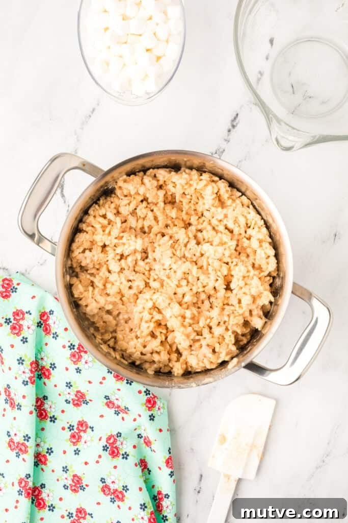 Browned Butter Rice Krispie Treats 9 Mixture of crispy rice cereal and melted marshmallows being stirred together in a large stainless steel pot.