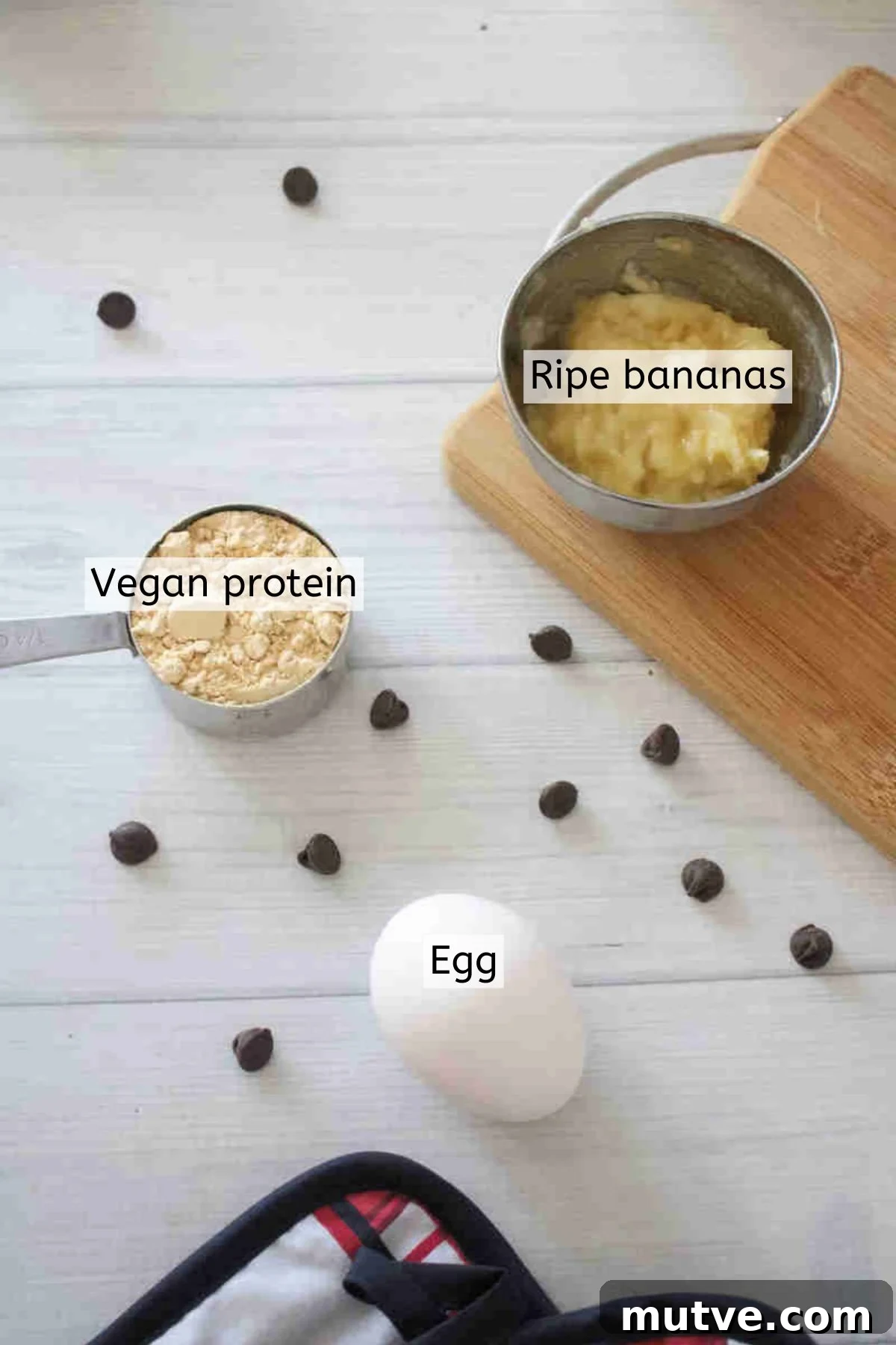 3-Ingredient Dairy-Free Protein Mug Cake 3 Mashed bananas, protein powder, and an egg with text labels over them and chocolate chips around them.