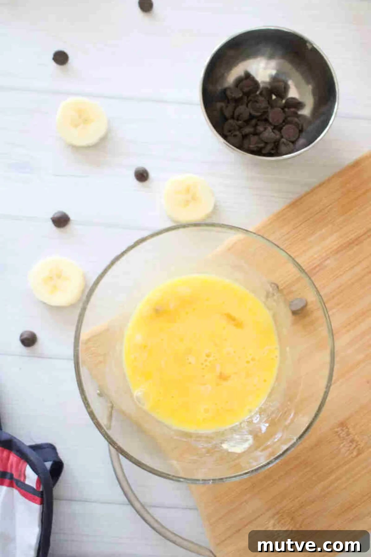 3-Ingredient Dairy-Free Protein Mug Cake 4 Glass bowl with raw egg in it on a cutting board.