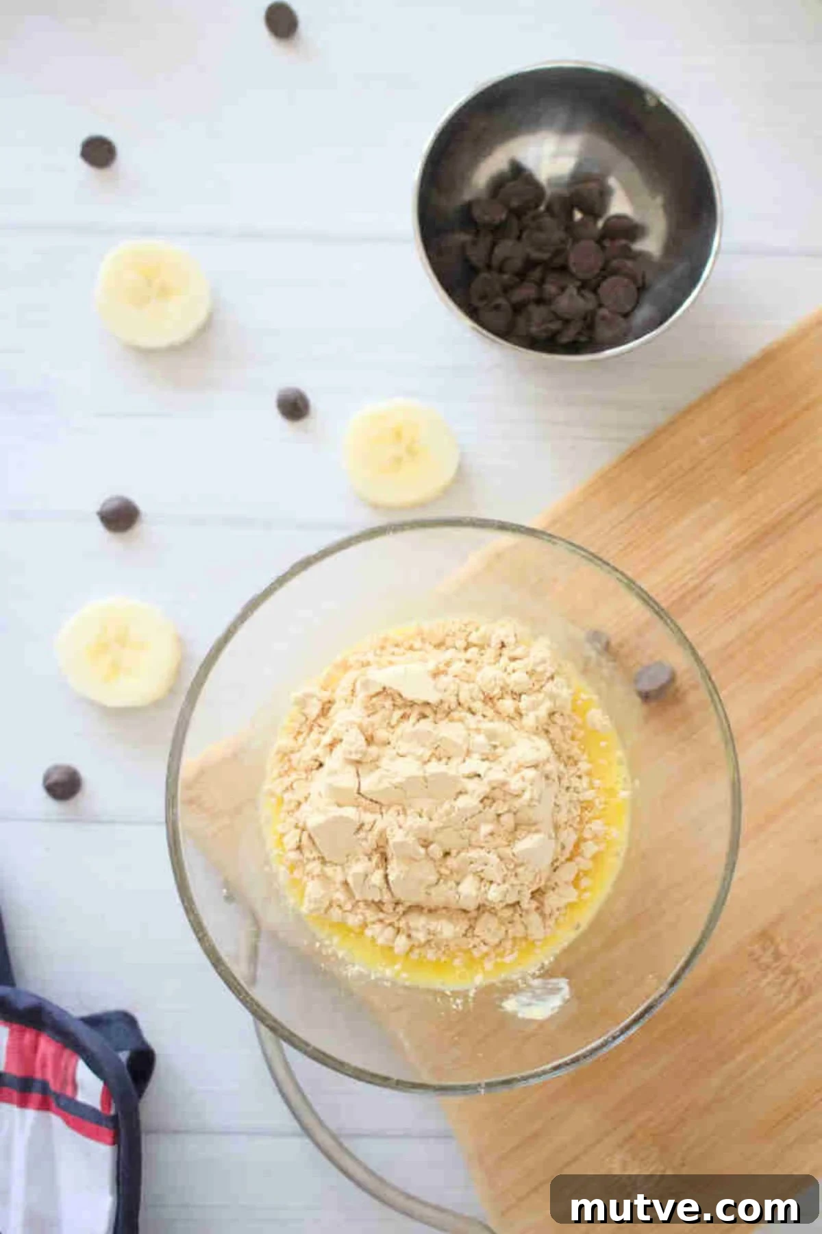 3-Ingredient Dairy-Free Protein Mug Cake 5 Glass bowl with raw eggs and protein powder in it on a cutting board.