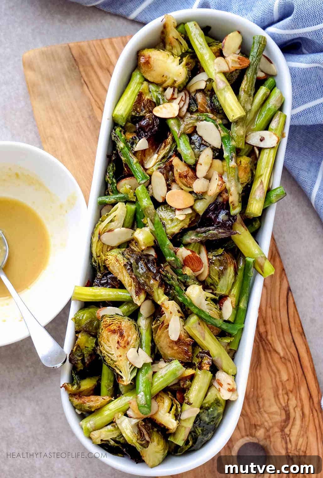 Oven Roasted Brussels Sprouts and Asparagus garnished with Almonds and finished with a lemon maple mustard sauce.