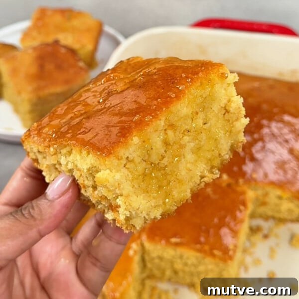 A close up photo of a slice of honey butter cornbread with honey butter drizzled on top