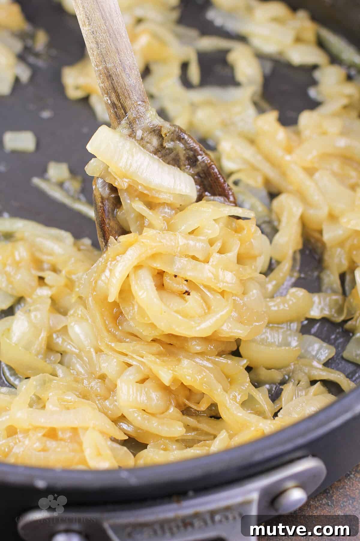 cooked onions in skillet with wood spoon