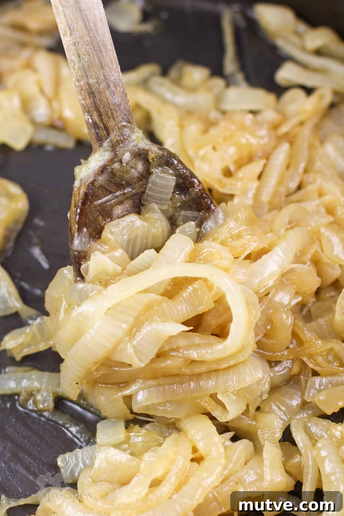 prepared onions in skillet with wood spoon