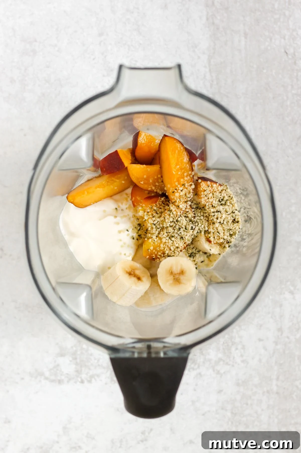 Ingredients for a peach banana smoothie in a blender.