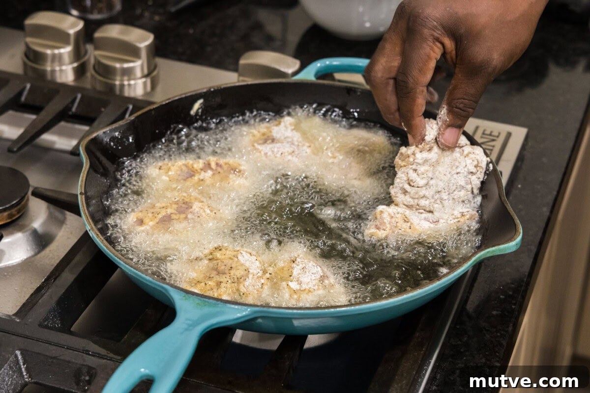 Crispy Chicken and Waffles Recipe with Maple Syrup 10 adding dredged chicken thighs to hot oil