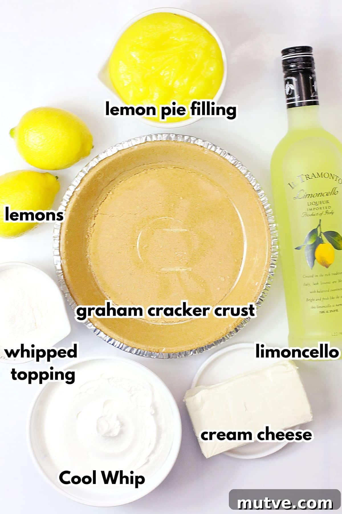 bowls of lemon pie filling, graham cracker crust, whipped topping, Cool Whip, cream cheese, lemons and limoncello on a counter.