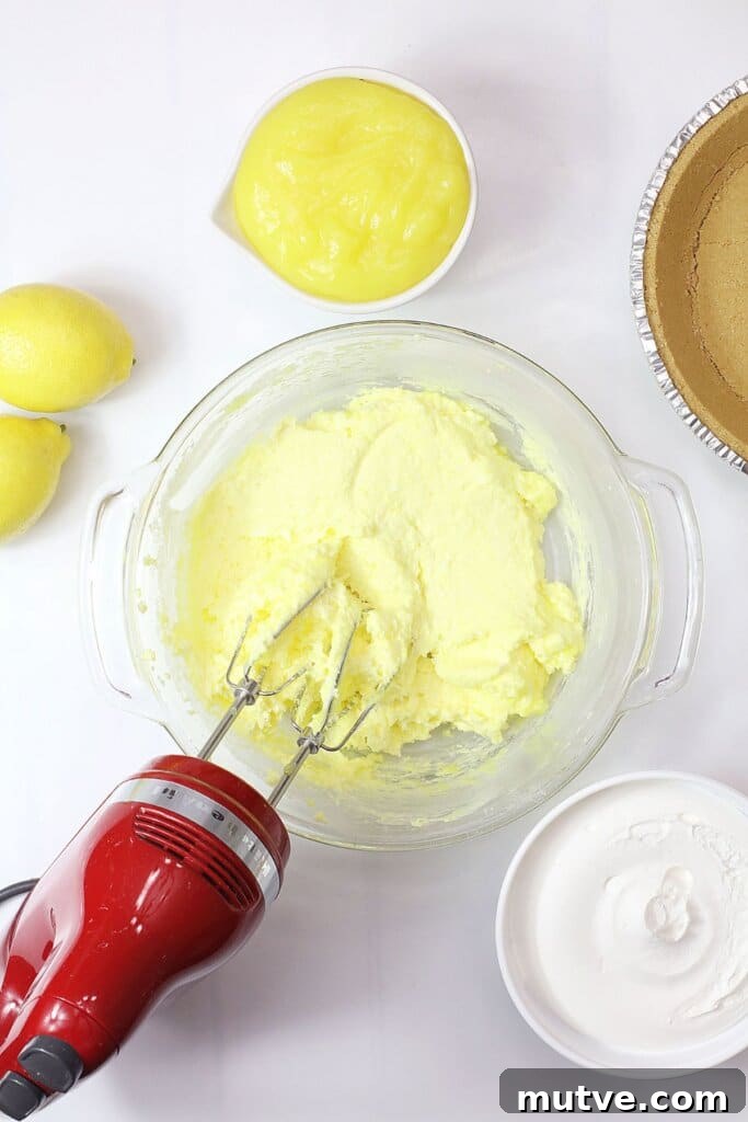 cream cheese and lemon pie filling being mixed in a glass mixing bowl.